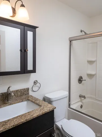 a bathroom with a granite countertop sink toilet and shower