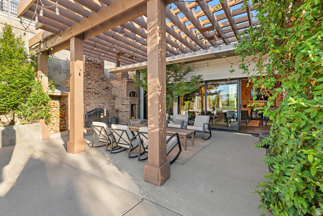 912 North Loafer Canyon Road Elk Ridge, UT 84651 - Photo 64 of 98 Expansive concrete patio featuring a wood-frame pergola, built-in brick fireplace, and integrated wood storage