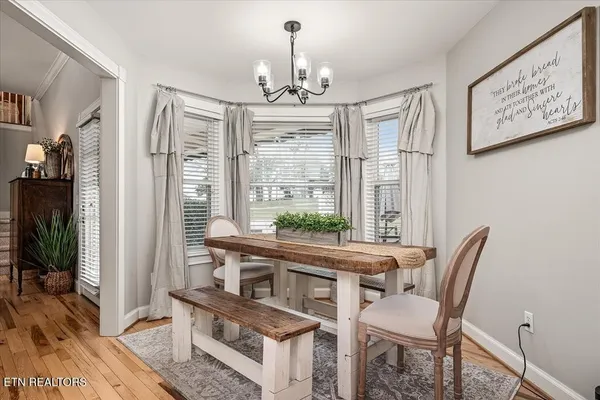 a dining room with wooden floor a chandelier a wooden table and chairs