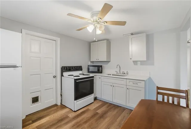 a kitchen with cabinets wooden floor and stainless steel appliances