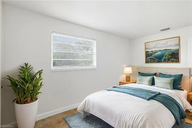 a bedroom with a bed a potted plant and a window