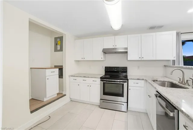 a kitchen with granite countertop a sink stove and refrigerator