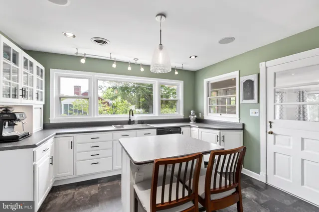 a kitchen with stainless steel appliances granite countertop a stove a sink dishwasher and white cabinets with wooden floor