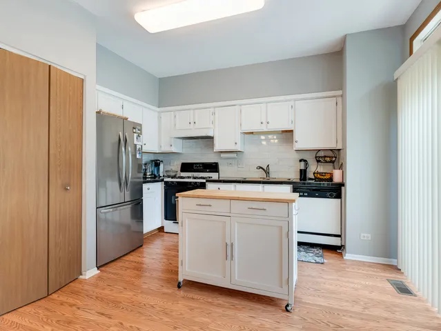 a kitchen with stainless steel appliances granite countertop a refrigerator stove and white cabinets
