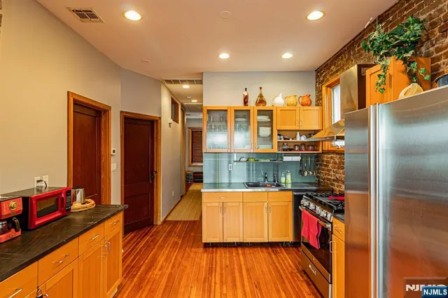 a view of a living room with stainless steel appliances wooden floor and a large window