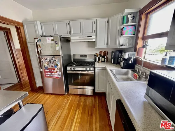 a kitchen with stainless steel appliances a stove a sink a refrigerator a window and cabinets