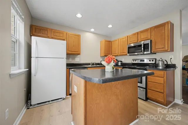 a kitchen with stainless steel appliances granite countertop a refrigerator a stove a sink and a microwave