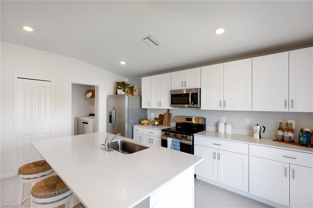 3717 40th Street Southwest Lehigh Acres, FL 33976 - Photo 3 of 30 a kitchen with stainless steel appliances a stove a sink a microwave a refrigerator and cabinets