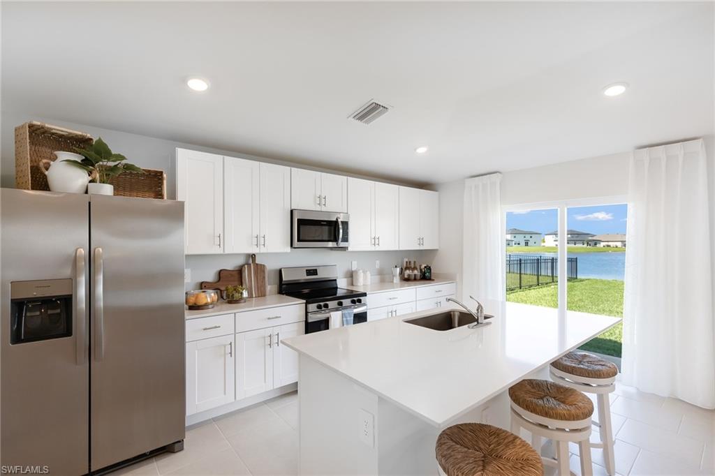 3717 40th Street Southwest Lehigh Acres, FL 33976 - Photo 6 of 30 a kitchen with white cabinets and stainless steel appliances