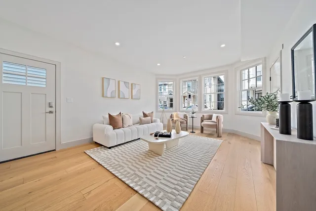 a living room with furniture large window and wooden floor