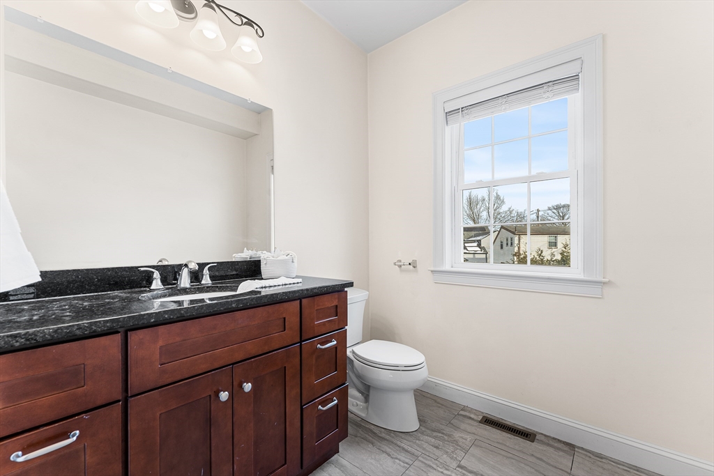 2 Mechanic Street, Unit 1 Medway, MA 02053 - Photo 12 of 32 a bathroom with a granite countertop toilet sink and mirror