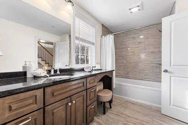a bathroom with a granite countertop sink a toilet a mirror and bathtub