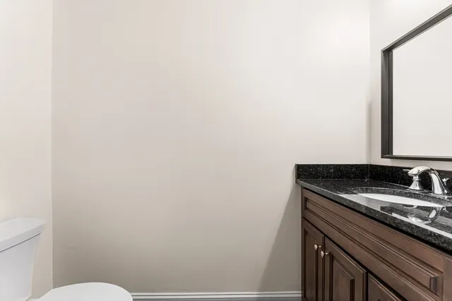 a bathroom with a granite countertop sink and a toilet