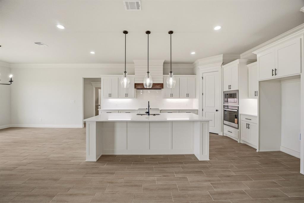 3155 Infinity Drive Weatherford, TX 76087 - Photo 12 of 39 Kitchen featuring white cabinets, an island with sink, stainless steel appliances, wood tiled floors, and ornamental molding
