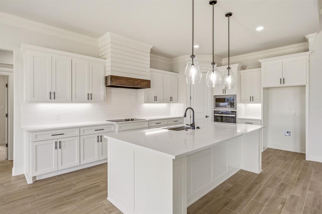 3155 Infinity Drive Weatherford, TX 76087 - Photo 13 of 39 Kitchen with white cabinetry, backsplash, wood tiled floors, a kitchen island with sink, and stainless steel appliances