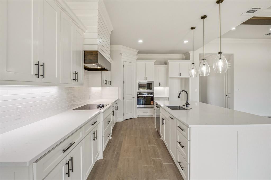 3155 Infinity Drive Weatherford, TX 76087 - Photo 14 of 39 Kitchen with an island with sink, white cabinets, stainless steel appliances, wood finish floors, and decorative backsplash