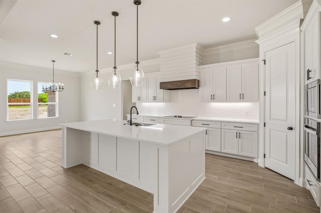 3155 Infinity Drive Weatherford, TX 76087 - Photo 15 of 39 Kitchen with crown molding, an island with sink, white cabinetry, and decorative backsplash