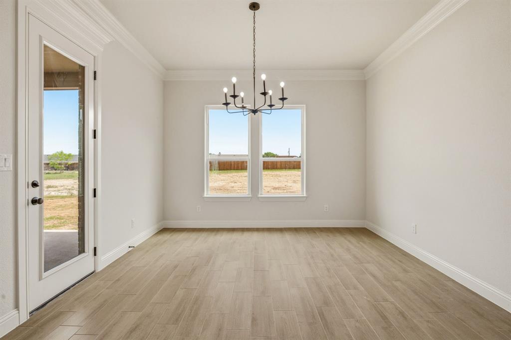 3155 Infinity Drive Weatherford, TX 76087 - Photo 16 of 39 Unfurnished dining area with hanging lights, wood finish floors, and ornamental molding