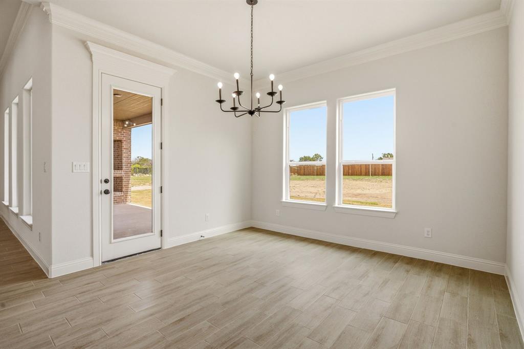 3155 Infinity Drive Weatherford, TX 76087 - Photo 17 of 39 Unfurnished dining area featuring a chandelier, light wood finished floors, and ornamental molding