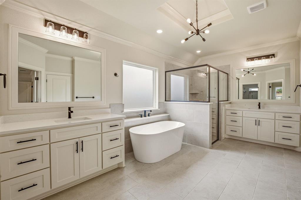 3155 Infinity Drive Weatherford, TX 76087 - Photo 21 of 39 Bathroom featuring a freestanding tub, a stall shower, two vanities, hanging lights, and ornamental molding