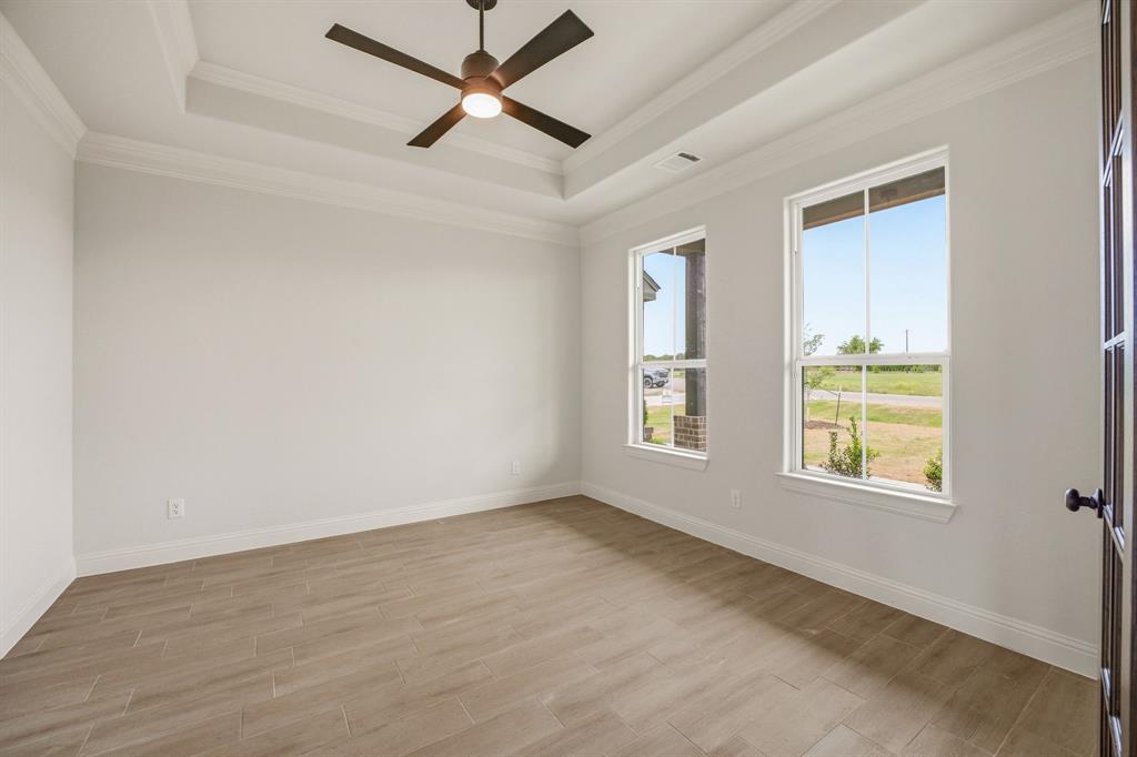 3155 Infinity Drive Weatherford, TX 76087 - Photo 5 of 39 Empty room with a ceiling fan, light wood finished floors, a tray ceiling, and crown molding