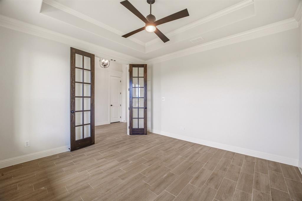 3155 Infinity Drive Weatherford, TX 76087 - Photo 7 of 39 Empty room featuring french doors, a ceiling fan, wood finish floors, a raised ceiling, and ornamental molding