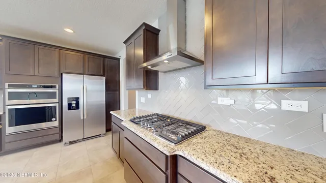 a kitchen with stainless steel appliances granite countertop a stove a refrigerator and a sink with wooden cabinets