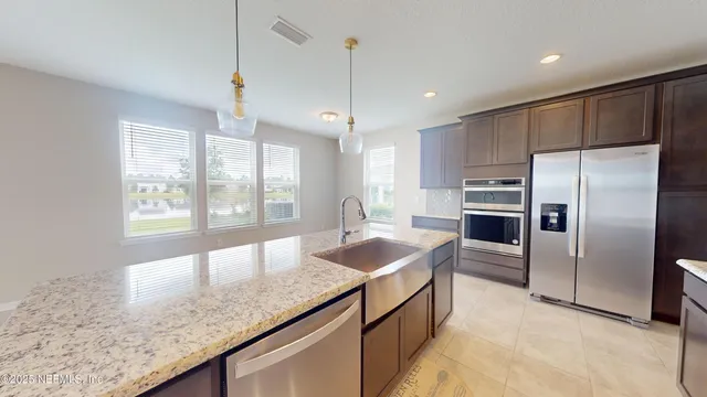 a kitchen with stainless steel appliances granite countertop a sink and a refrigerator