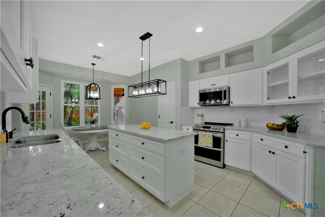 103 Sierra Ridge Drive San Marcos, TX 78666 - Photo 14 of 43 a kitchen with stainless steel appliances kitchen island granite countertop a sink and white cabinets