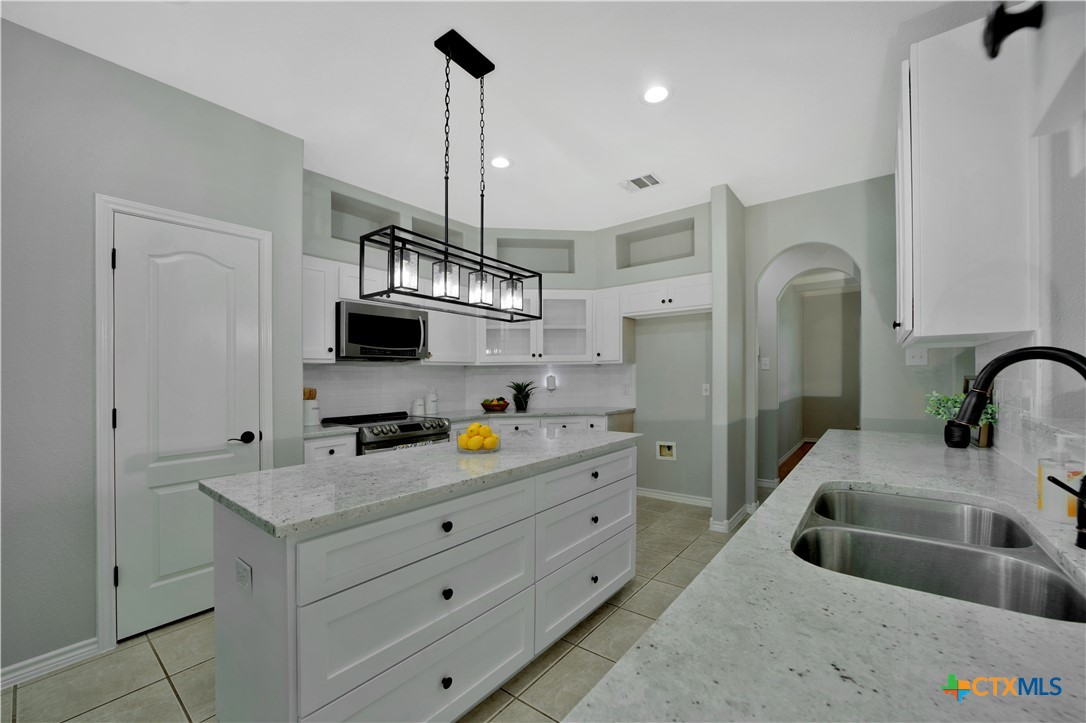 103 Sierra Ridge Drive San Marcos, TX 78666 - Photo 15 of 43 a kitchen with stainless steel appliances a sink a chandelier and a view of living room