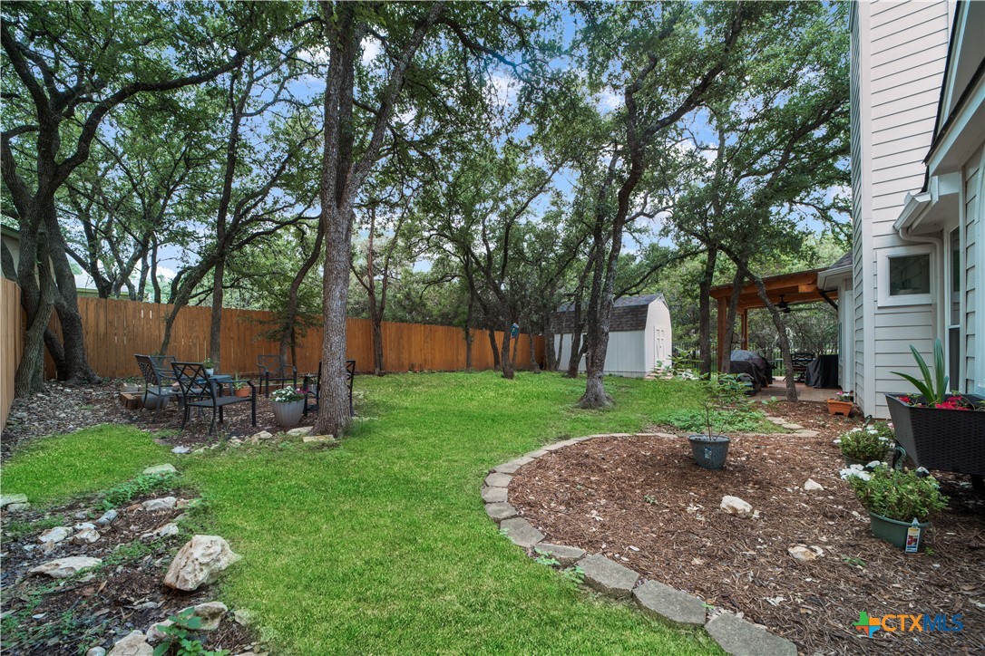 103 Sierra Ridge Drive San Marcos, TX 78666 - Photo 35 of 43 a view of a backyard with table and chairs and a large tree