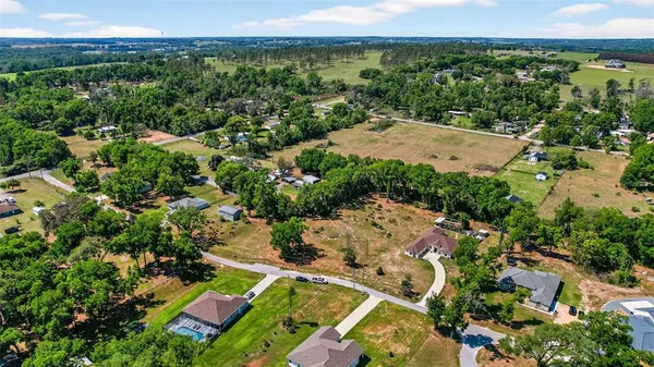 an aerial view of residential houses with outdoor space and trees all around