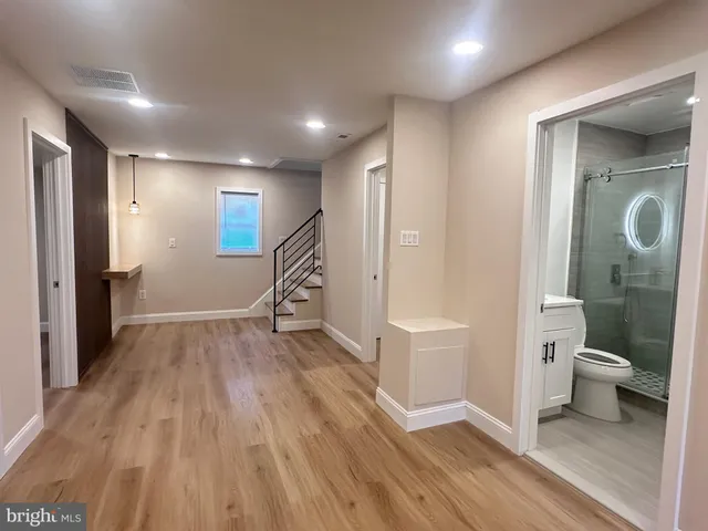 a view of a hallway with wooden floor and a bathroom