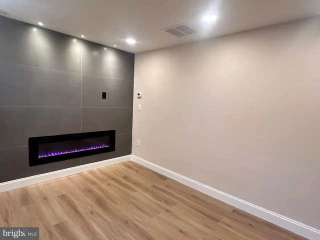 a view of an empty room with wooden floor and a fireplace