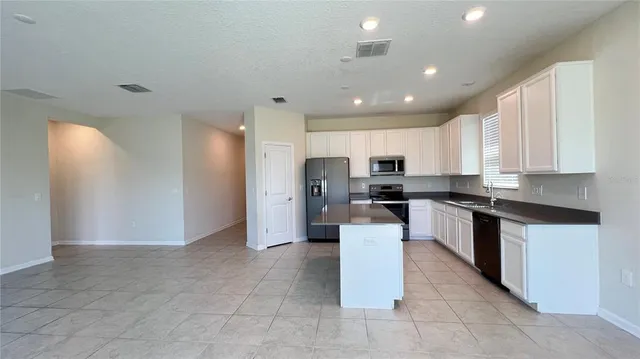 a kitchen with stainless steel appliances granite countertop a refrigerator a sink a stove a microwave and island