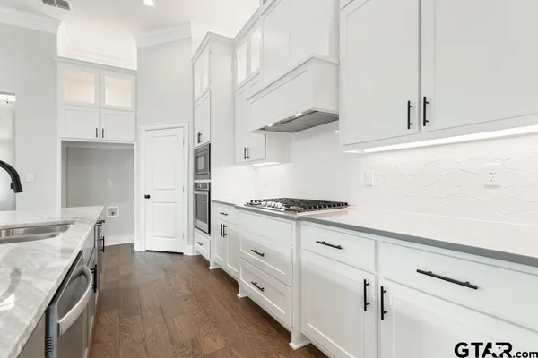 a kitchen with stainless steel appliances a stove a sink and white cabinets