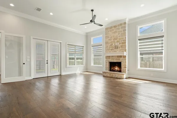 a view of an empty room with wooden floor fireplace and a window