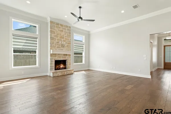 an empty room with wooden floor fireplace and windows