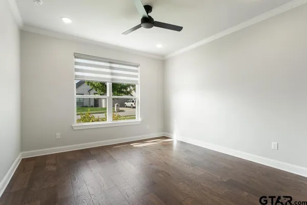 an empty room with wooden floor ceiling fan and windows