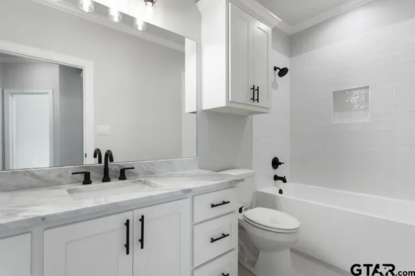 a bathroom with a granite countertop toilet sink and mirror