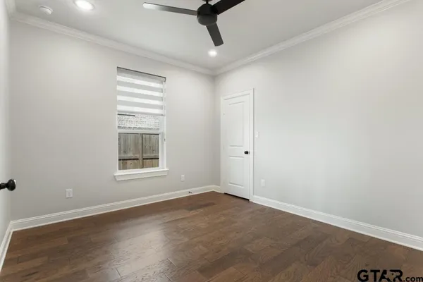 an empty room with wooden floor cabinet and windows