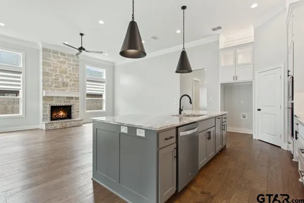 a kitchen with stainless steel appliances granite countertop a sink a stove and a wooden floor