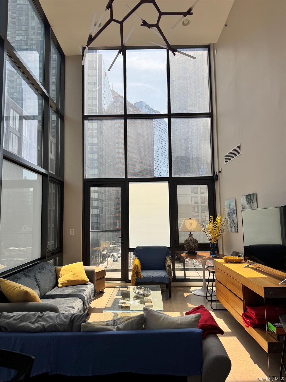 24-12 42nd Road, Unit 6C Queens, NY 11101 - Photo 4 of 12 a living room with furniture and a floor to ceiling window