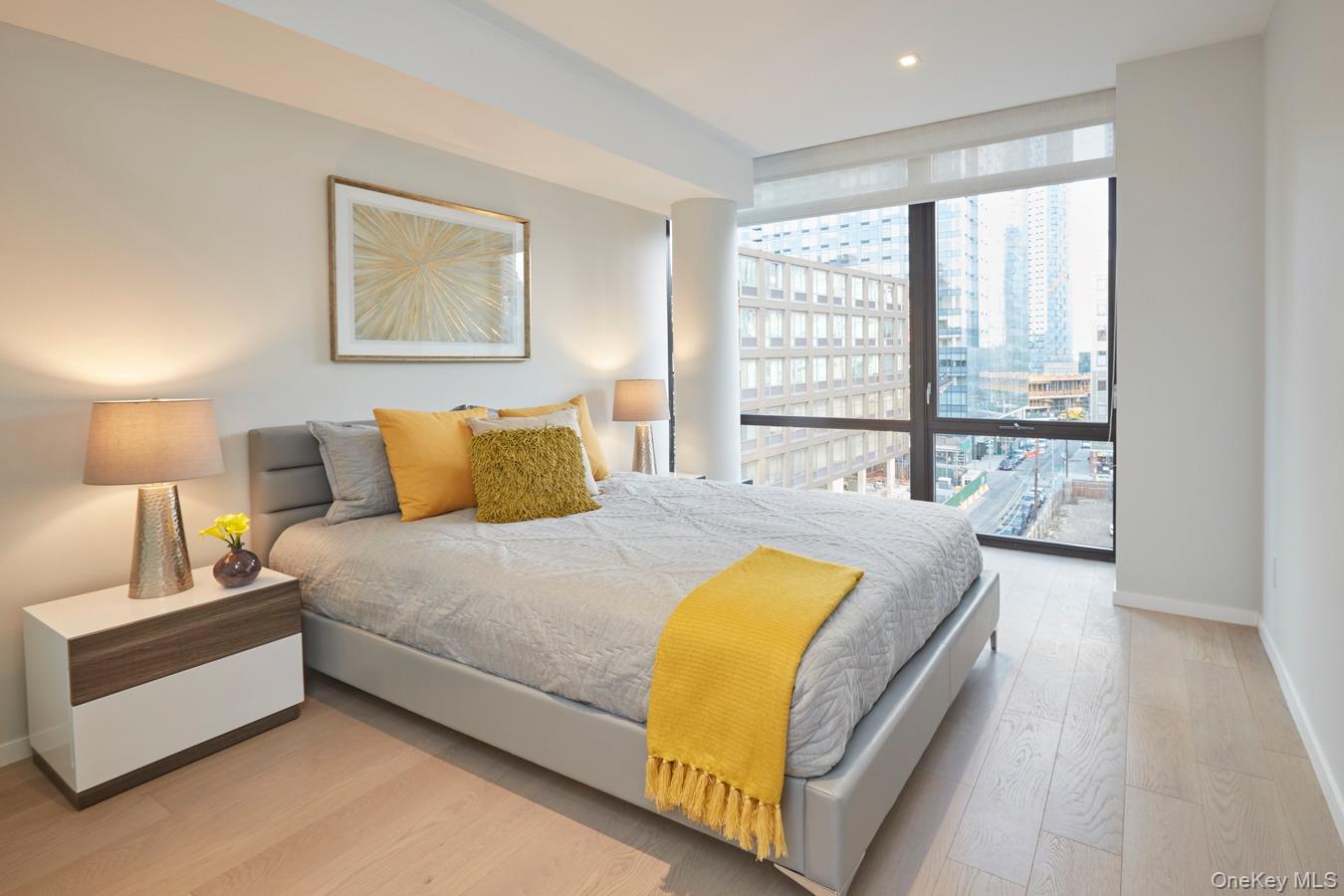 24-12 42nd Road, Unit 6C Queens, NY 11101 - Photo 6 of 12 a bedroom with a large bed and a large window