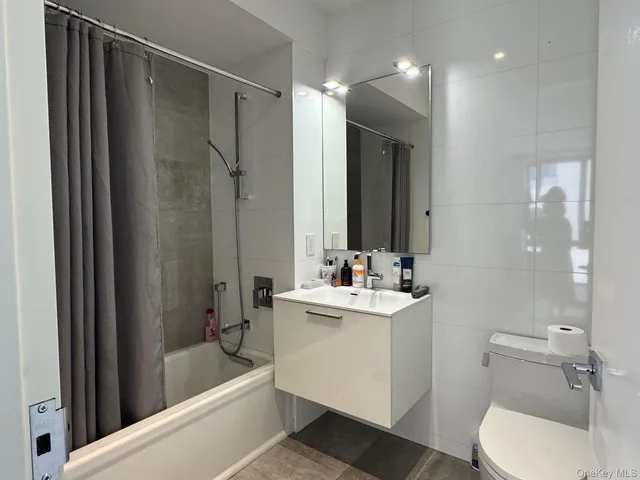 a bathroom with a bathtub shower sink mirror and toilet