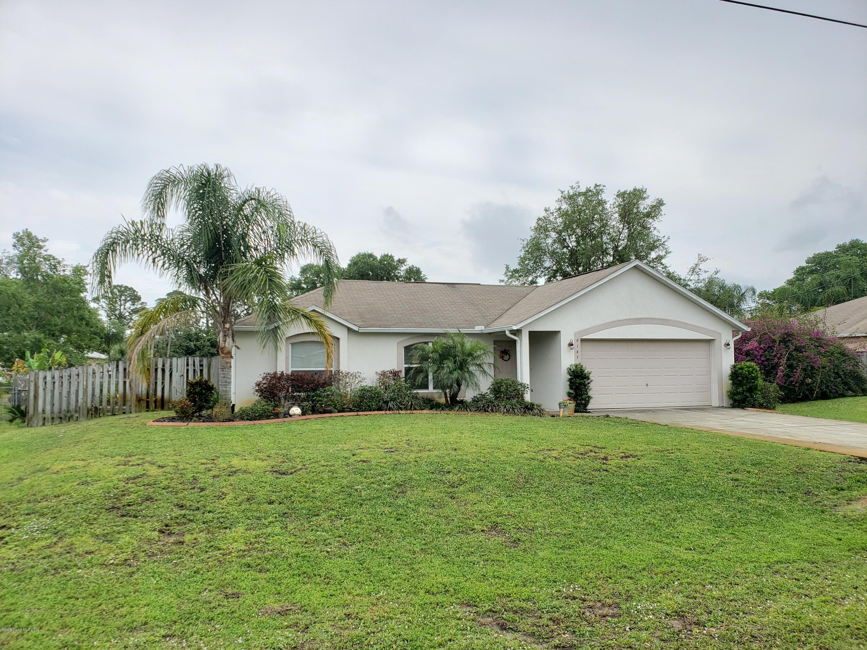 front view of a house and a yard with a trees