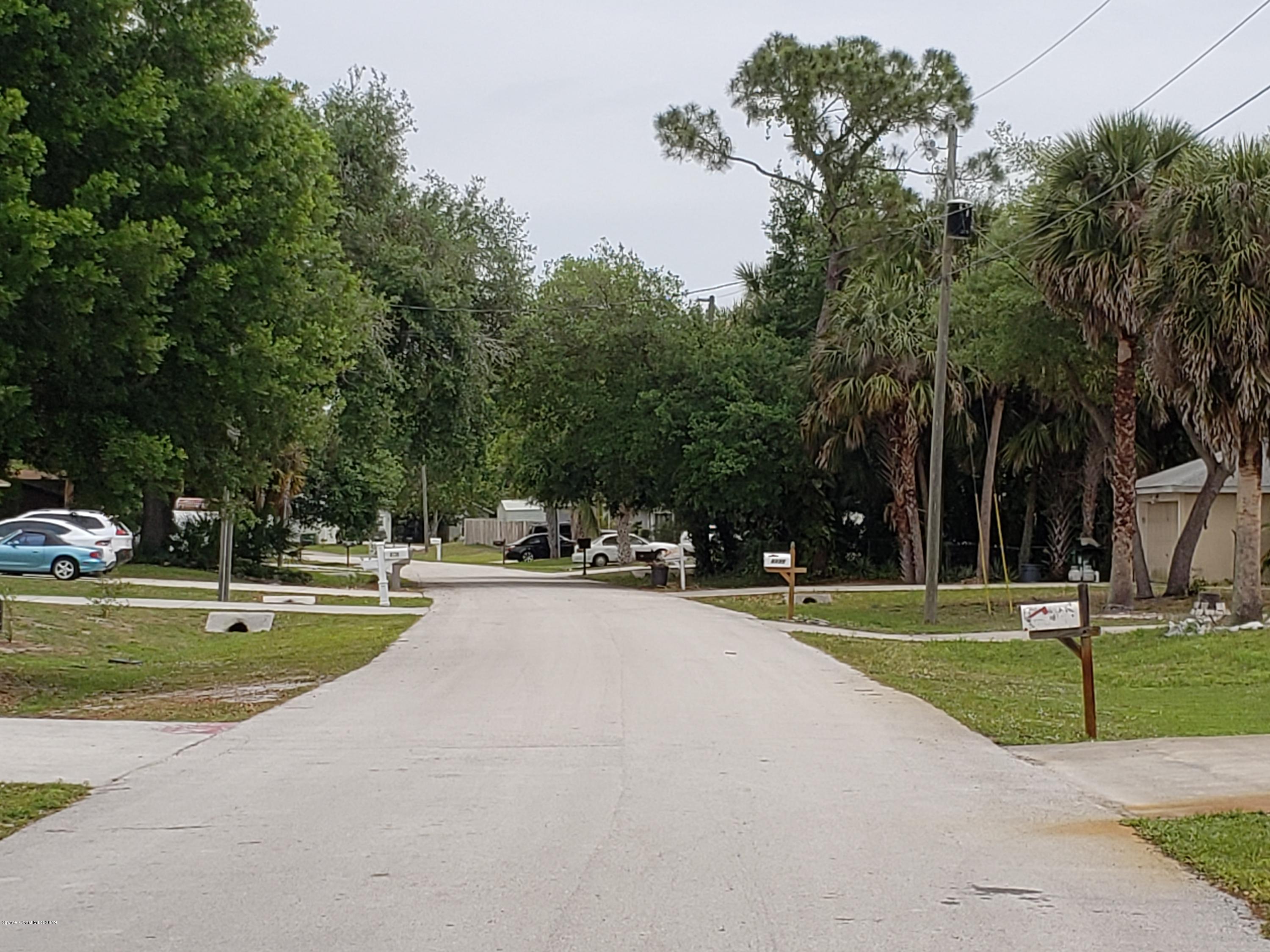 6145 Adina Road Cocoa, FL 32927 - Photo 3 of 34 a view of a swimming pool and a yard with plants and large trees