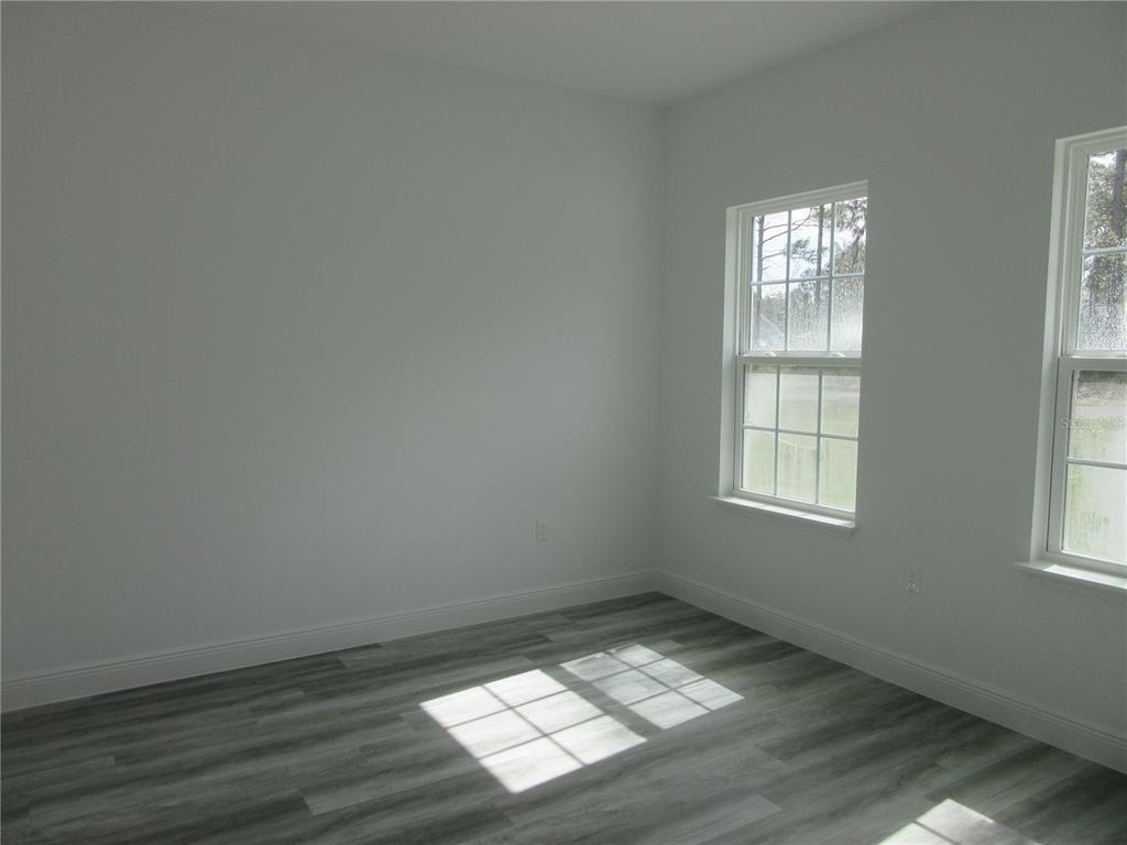 6765 Southwest 152nd Lane Road Ocala, FL 34473 - Photo 11 of 14 an empty room with wooden floor and windows