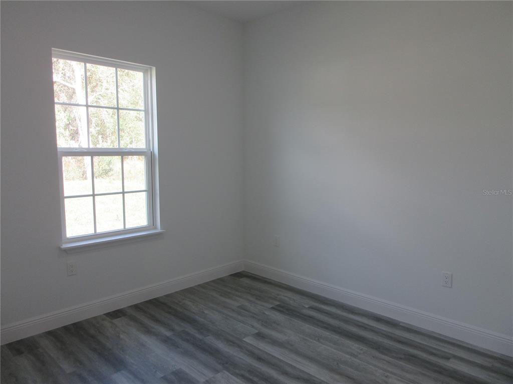 6765 Southwest 152nd Lane Road Ocala, FL 34473 - Photo 12 of 14 an empty room with wooden floor and windows