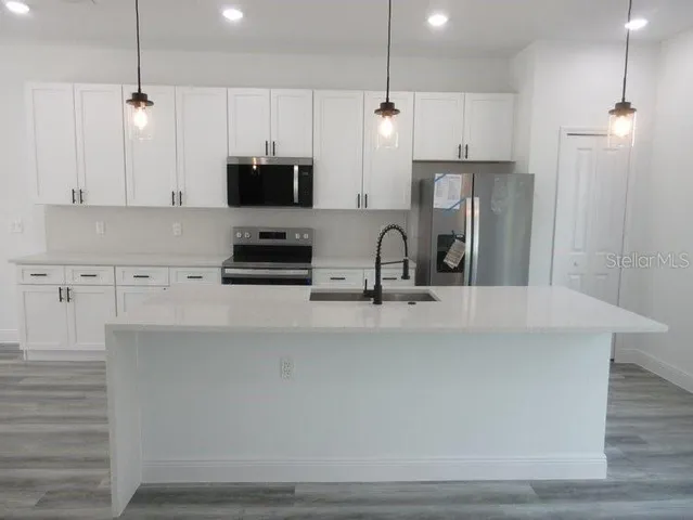a kitchen with stainless steel appliances a sink a stove a refrigerator and cabinets